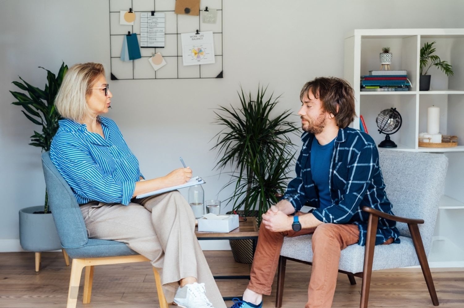 Counselor and male client converse while seated across from each other in a cozy office.